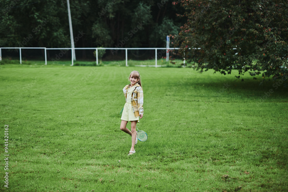 Teenage girl playing badminton on green grass in summer park Teenage girl playing badminton on green grass in summer park