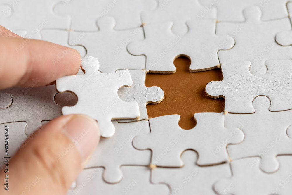 Obraz premium Hand holding a puzzle pieces, completing jigsaw puzzle. business concept. Selective focus.