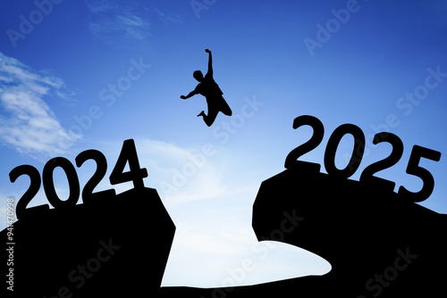 Concept Happy new year 2025 Silhouette image of happy man jump from 2024 up to 2025 on beautiful blue sky.