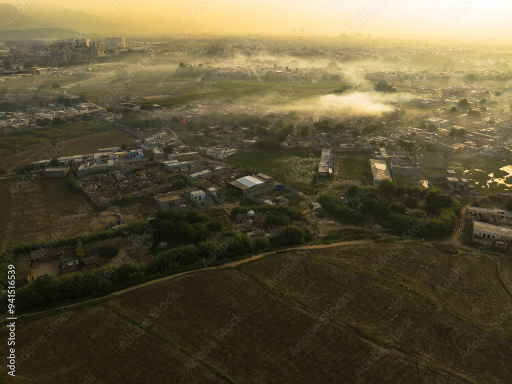 Aerial view of fields, residencial parts of the city and a bit of marglla hills, during a foggy surise, Islamabad, Islamabad capital territory, Paksitan Aerial view of fields, residencial parts of the city and a bit of marglla hills, during a foggy surise, Islamabad, Islamabad capital territory, Paksitan