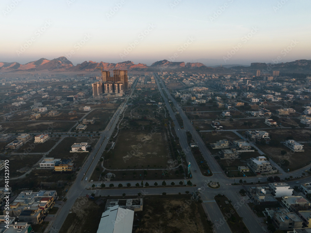 Aerial view of streets, a park, a building under construction and hills ...