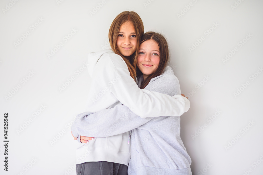 Two best girlfriends together on white studio wearing hoodies Two best girlfriends together on white studio wearing hoodies