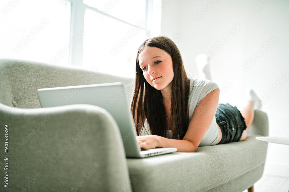 Naklejka premium teen using laptop sit on sofa in the living room.