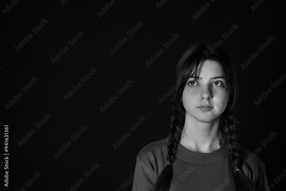 Portrait of teenage girl on dark background, space for text. Black and white effect Portrait of teenage girl on dark background, space for text. Black and white effect