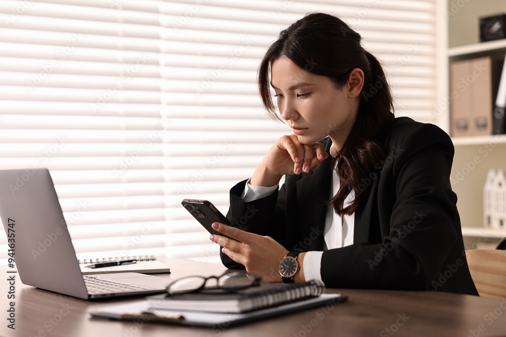 Beautiful young businesswoman using smartphone in office Beautiful young businesswoman using smartphone in office