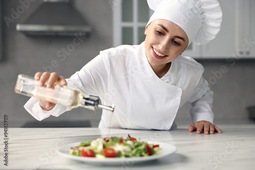 Professional chef pouring oil onto delicious salad at white marble table in kitchen