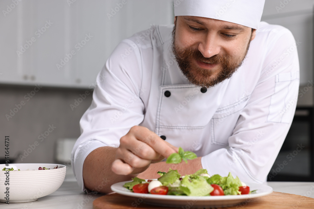 Professional chef decorating delicious salad with basil at table in kitchen Professional chef decorating delicious salad with basil at table in kitchen