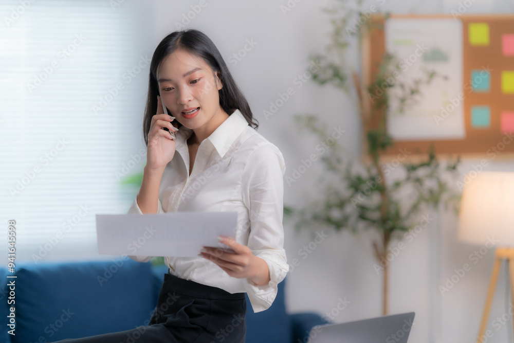 Asian businesswomen working in the office talking the phone, and checking the report Asian businesswomen working in the office talking the phone, and checking the report