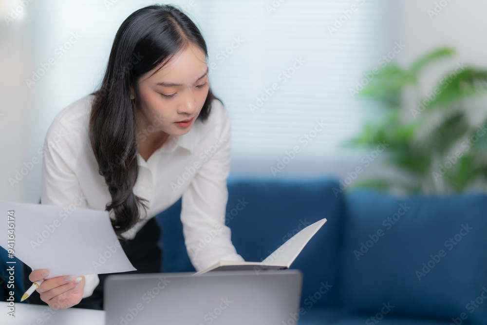 Asian businesswomen working in the office talking the phone, and checking the report Asian businesswomen working in the office talking the phone, and checking the report