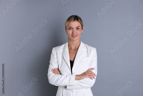 Beautiful woman in stylish white suit on grey background