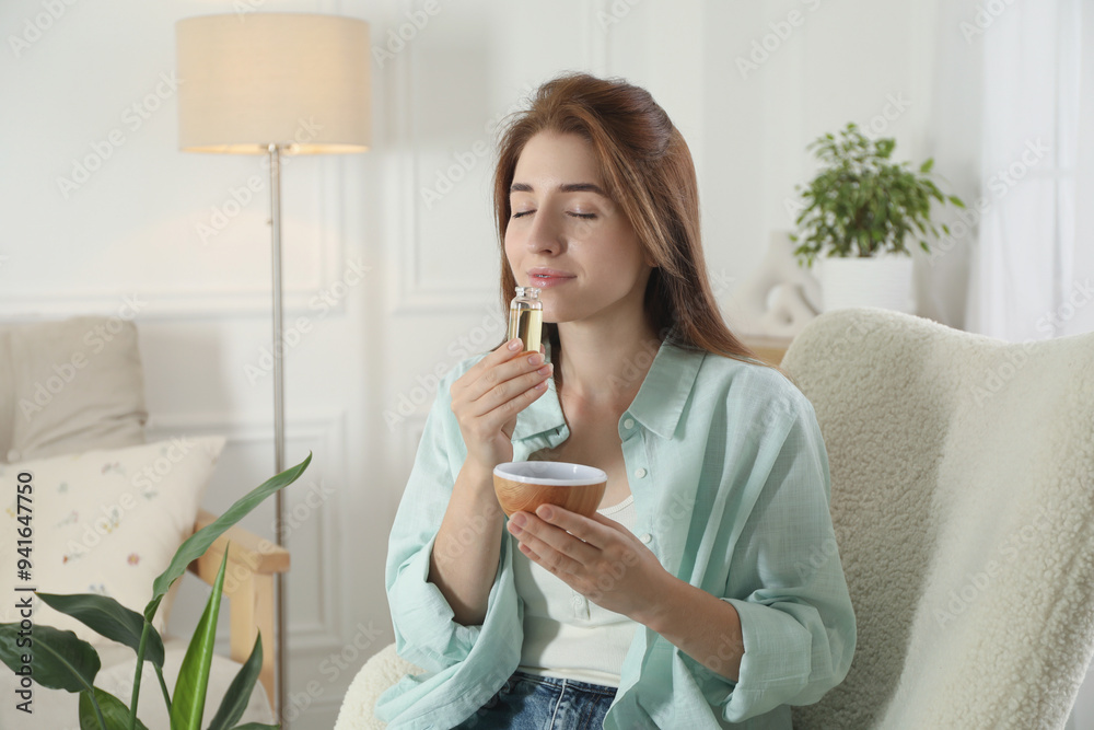 Woman with aroma diffuser and bottle of essential oil at home Woman with aroma diffuser and bottle of essential oil at home