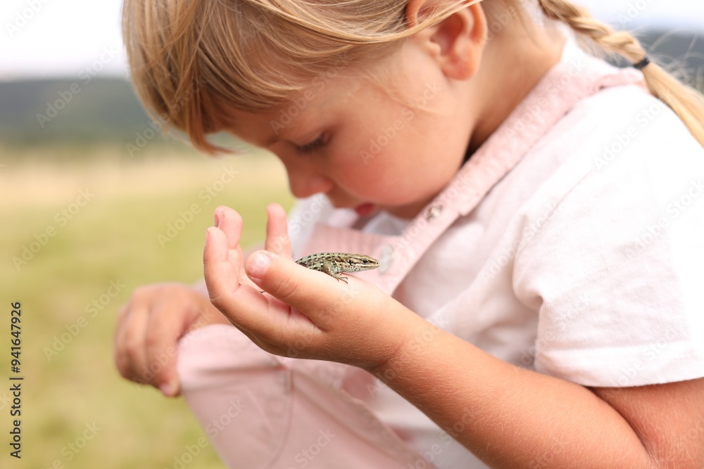 Happy little girl holding small lizard outdoors Happy little girl holding small lizard outdoors