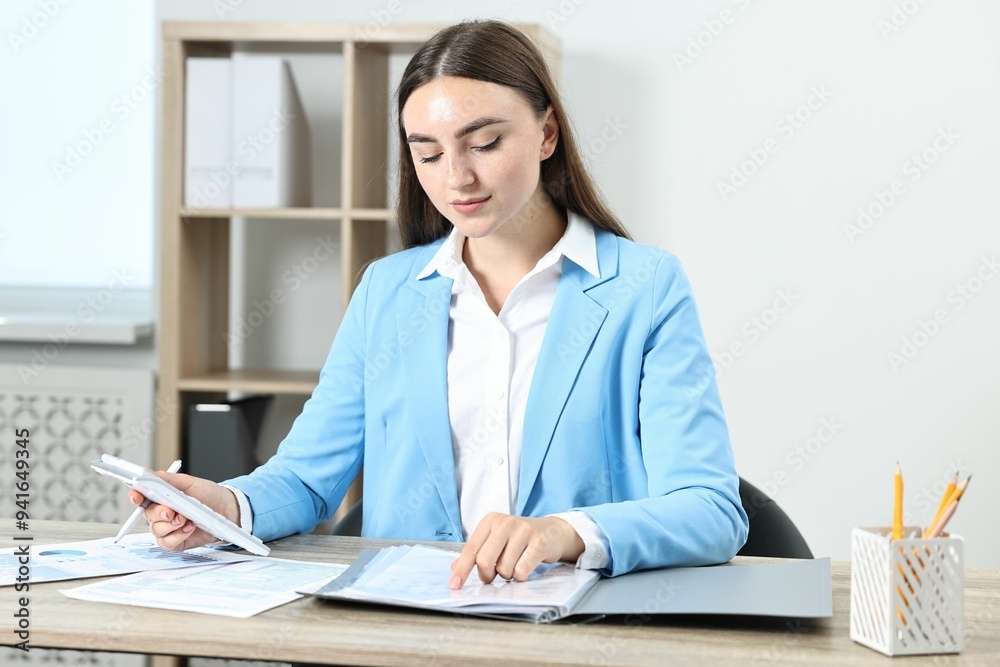 Budget planning. Beautiful young woman with papers and calculator at wooden table in office Budget planning. Beautiful young woman with papers and calculator at wooden table in office
