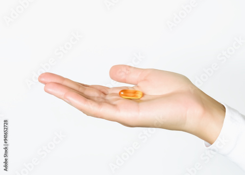 woman holding yellow capsule pill in her palm