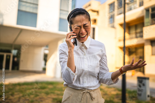 Happy mature japanese business woman talk on mobile phone