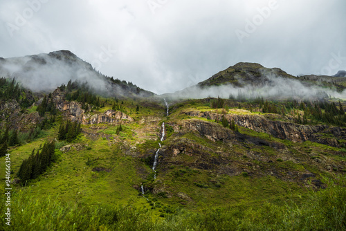 Distant mountain waterfall in the early morning with low clouds