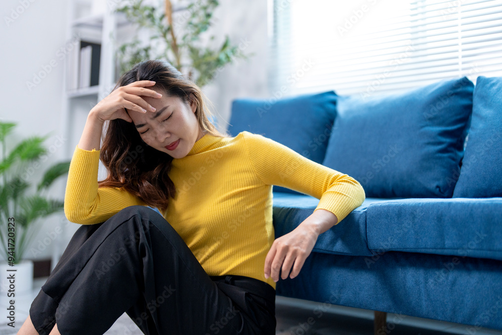 Young asian woman feeling sick and having a headache at home on the floor Young asian woman feeling sick and having a headache at home on the floor