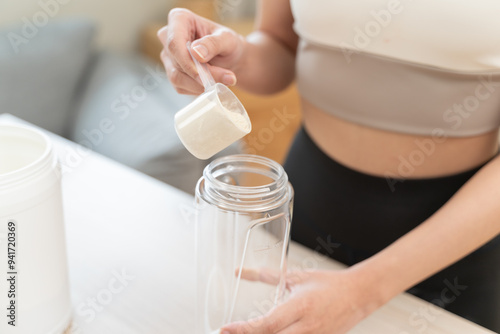 Diet meal replacement for weight loss, asian young woman in sportswear, hand in holding scoop making protein into bottle photo