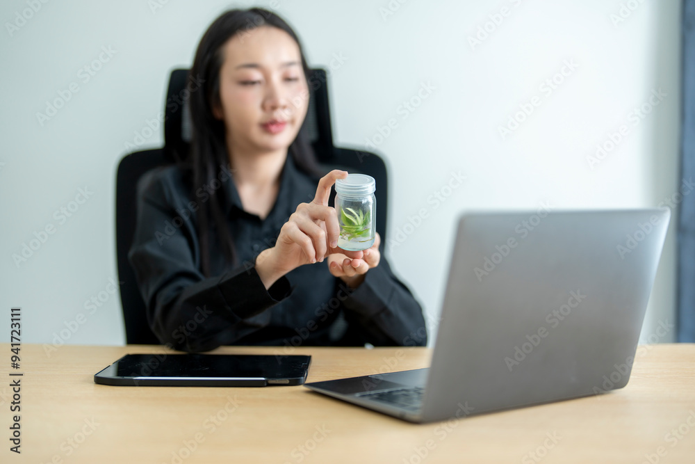 Asian businesswoman showing a plant growing in a jar during a video call Asian businesswoman showing a plant growing in a jar during a video call