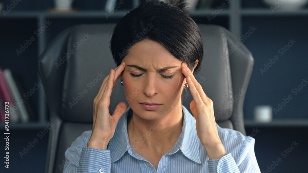 Stressed businesswoman suffering from headache at Stressed businesswoman suffering from headache at