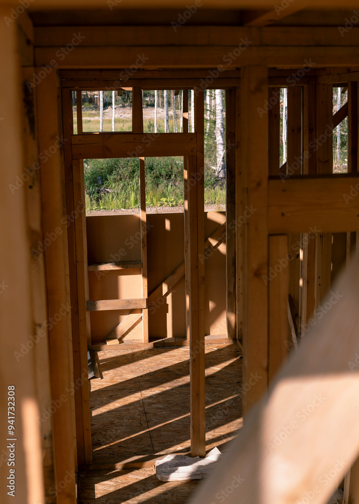 Interior view of wooden frame structure of a house under construction with visible wall openings. Residential construction project concept. Interior view of wooden frame structure of a house under construction with visible wall openings. Residential construction project concept.