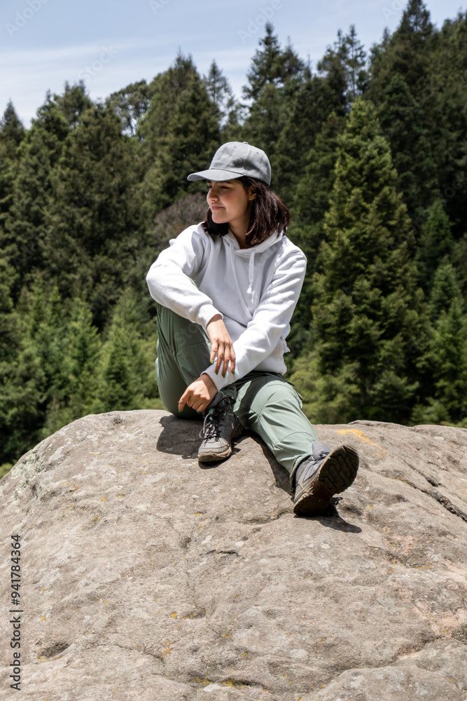 Woman sitting on a rock overlooking the forest landscape Woman sitting on a rock overlooking the forest landscape