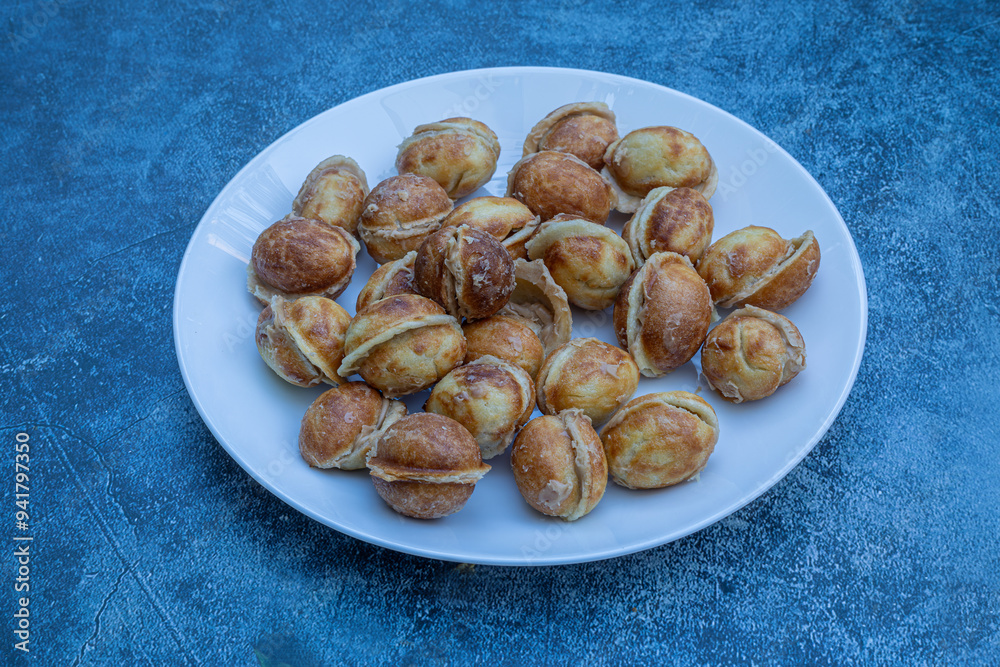 A bowl of delicious walnut-shaped cookies made with boiled condensed milk in a white plate, with a walnut-like appearance made in a cast mold.