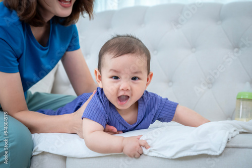 A woman is kissing a baby while holding a bottle. The woman is wearing a blue shirt 