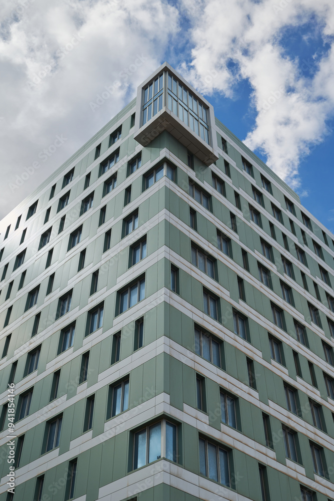 Corner of a residential building with many windows and a cloudy sky in the background Corner of a residential building with many windows and a cloudy sky in the background