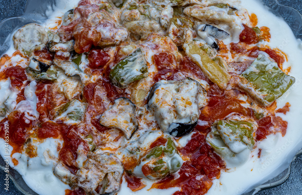 Fried potatoes, eggplants and peppers with garlic, yoghurt and sauce poured on top.