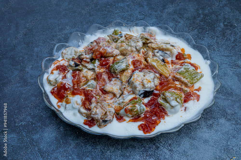 Fried potatoes, eggplants and peppers with garlic, yoghurt and sauce poured on top.