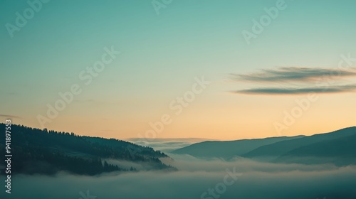 Misty valley during sunrise with soft clouds and mountains in the distance
