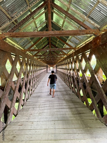 people walking on wooden bridge, lobu bridge in the area between Bunta and Pagimana Banggai Regency, Central Sulawesi. This bridge was made in 1940 in the Dutch era, hand made. photo