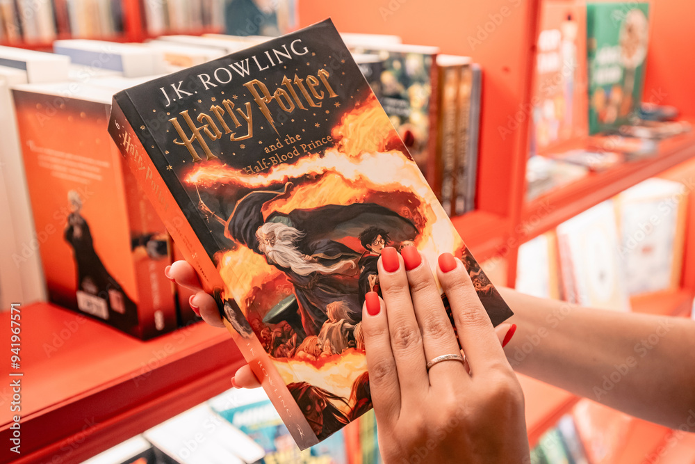 Fototapeta premium 09 July 2024, Istanbul, Turkey: A fan holding the Harry Potter book Half-Blood Prince in a bookstore, browsing the pages