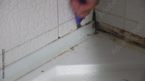 Renovation of old shower bathtub caulk insulation in close up view.