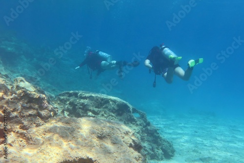 Wallpaper Mural Pair of scuba divers exploring shallow rocky seascape in the clear water. Underwater photography from scuba diving. Landscape under the sea, travel photo. Ocean and swimming divers. Torontodigital.ca
