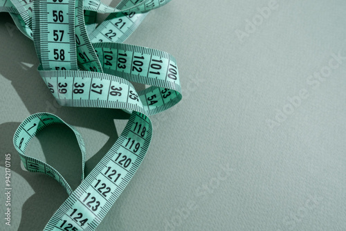 Green measuring tape on a light background. Tool for measuring length and volume. Tape for measuring in the clothing industry or the volume of the human body 