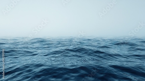  A vast expanse of water with ripples in the foreground and a soft blue sky behind