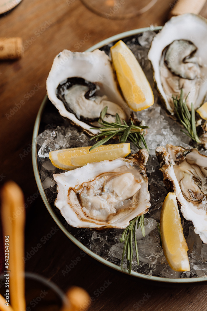 Fresh oysters on ice served with lemon wedges and rosemary, perfect for gourmet seafood lovers Fresh oysters on ice served with lemon wedges and rosemary, perfect for gourmet seafood lovers