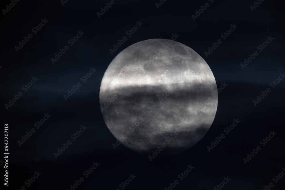 photograph of the full moon partially covered with clouds