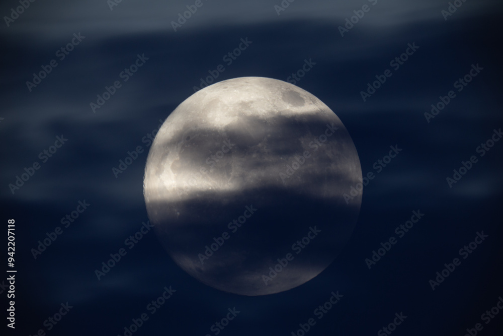 photograph of the full moon partially covered with clouds