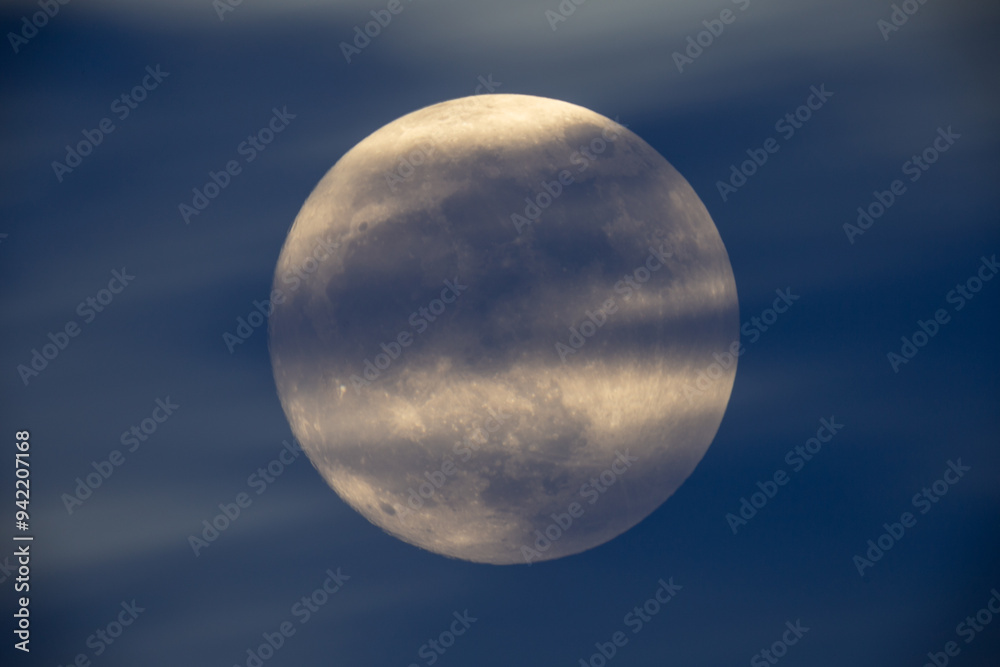 photograph of the full moon partially covered with clouds
