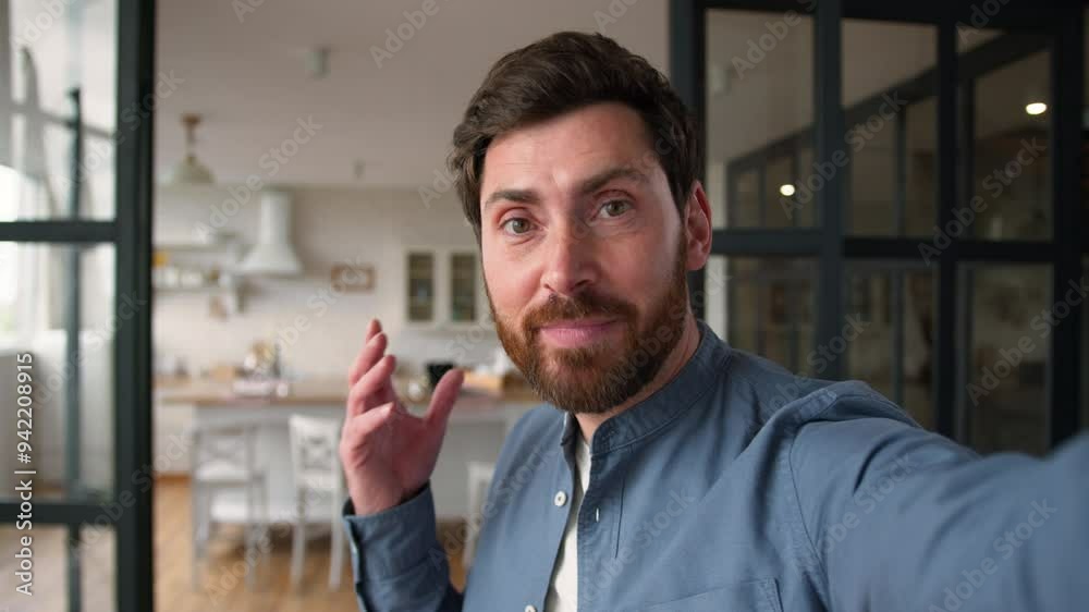 Smiling Caucasian adult man blogger holding mobile phone device camera positive male father talking speak on video blogging glad dad guy waving hand greeting online streaming filming room tour at home Smiling Caucasian adult man blogger holding mobile phone device camera positive male father talking speak on video blogging glad dad guy waving hand greeting online streaming filming room tour at home