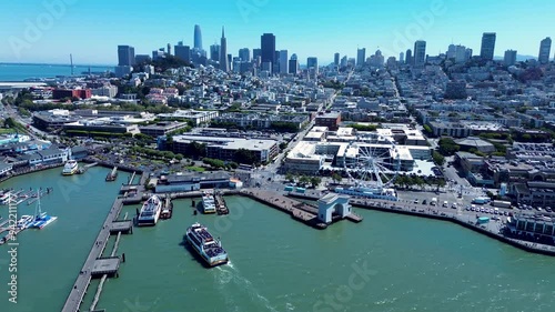 Drone aerial landscape of San Francisco city CBD downtown wharf Embarcadero ship ferry docking at pier 41 bay area with Ferris wheel USA America travel tourism infrastructure
