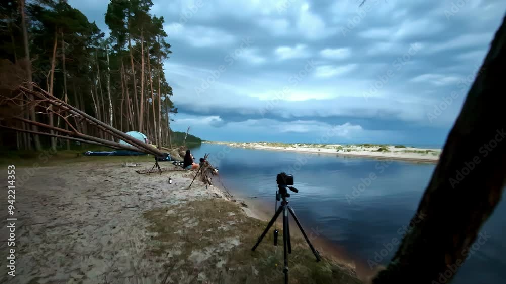 Riverside with cameras set up on tripods, surrounded by trees and a dramatic, cloudy sky Riverside with cameras set up on tripods, surrounded by trees and a dramatic, cloudy sky