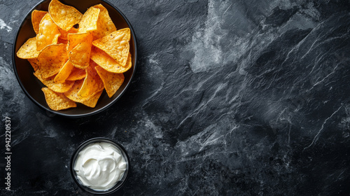 A bowl of chips and a bowl of dip on a black counter photo