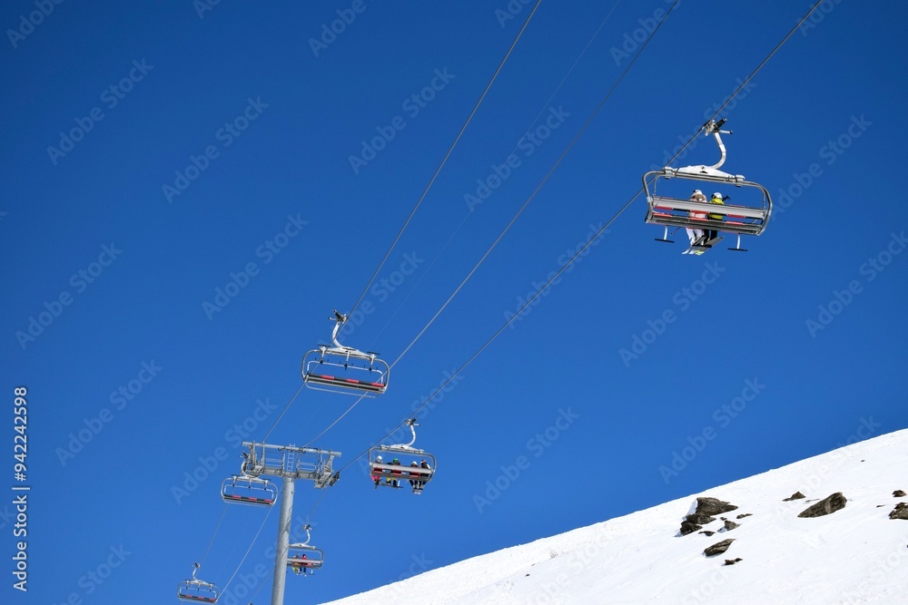 Overhead chair lifts for skiers and snowboarders on a clear, sunny day in a French ski resort Overhead chair lifts for skiers and snowboarders on a clear, sunny day in a French ski resort