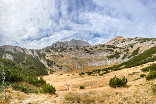 A meadow overgrown with dry grass on the road from Banderitsa hut to Kazana shelter against Hihren and Kutelo peaks. Autumn panoramic view of the Pirin highlanda, Bulgaria. photo