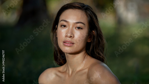 A woman with a natural glow gazes softly into the distance, her serene expression complemented by the peaceful outdoor setting and soft lighting.