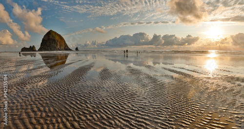 USA, Oregon, Cannon Beach. Sunset golden colors with ripples in sandy beach and The Haystack Rock